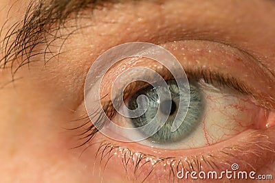 The manâ€™s eye is gray-blue with red veins on it very close Stock Photo